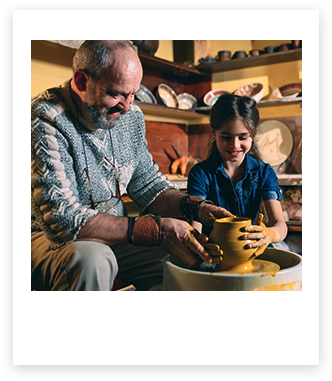 Người đàn ông thao tác trên bàn xoay làm gốm với một đứa trẻ